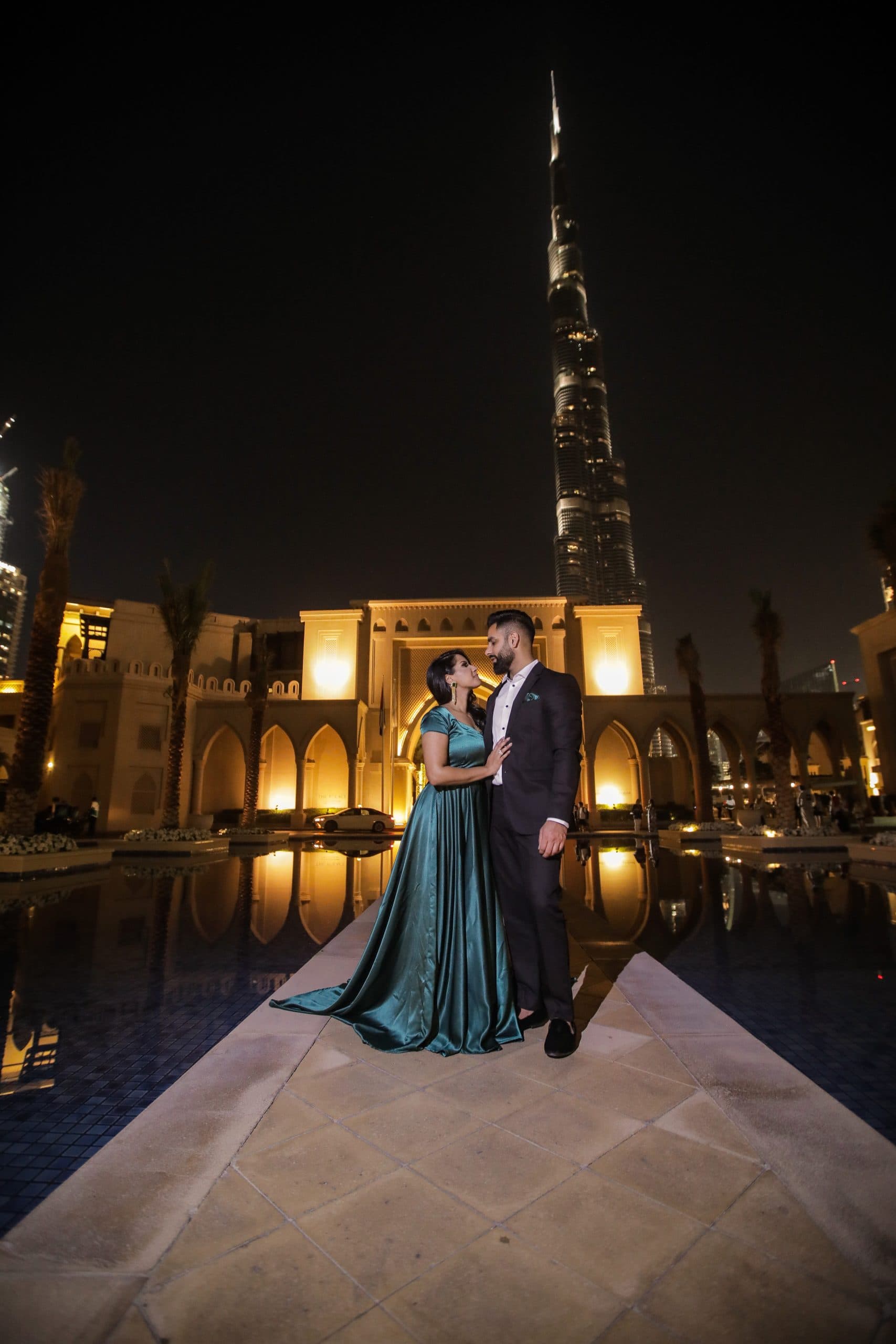 An evening portrait of a couple at the Palace Downtown with the Burj Khalifa lit behind them, photographed by Taj Raj Events